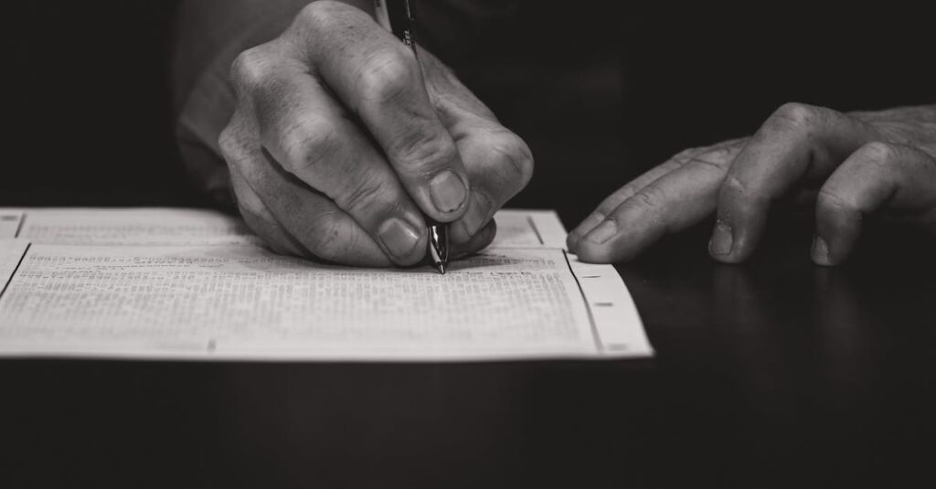 Monochrome image of a hand writing on a document, emphasizing attention to detail.
